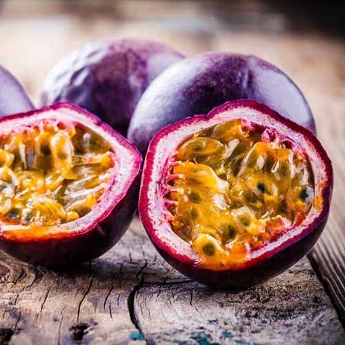 Une photo de produit carrée d'un fruit de la passion pourpre possum coupé en deux avec les graines.