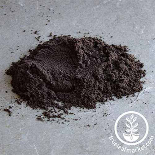 Une image carrée rapprochée d'un tas d'inoculant de couleur foncée ensemble sur une surface en béton. En bas à droite du cadre se trouve un logo circulaire blanc avec du texte.