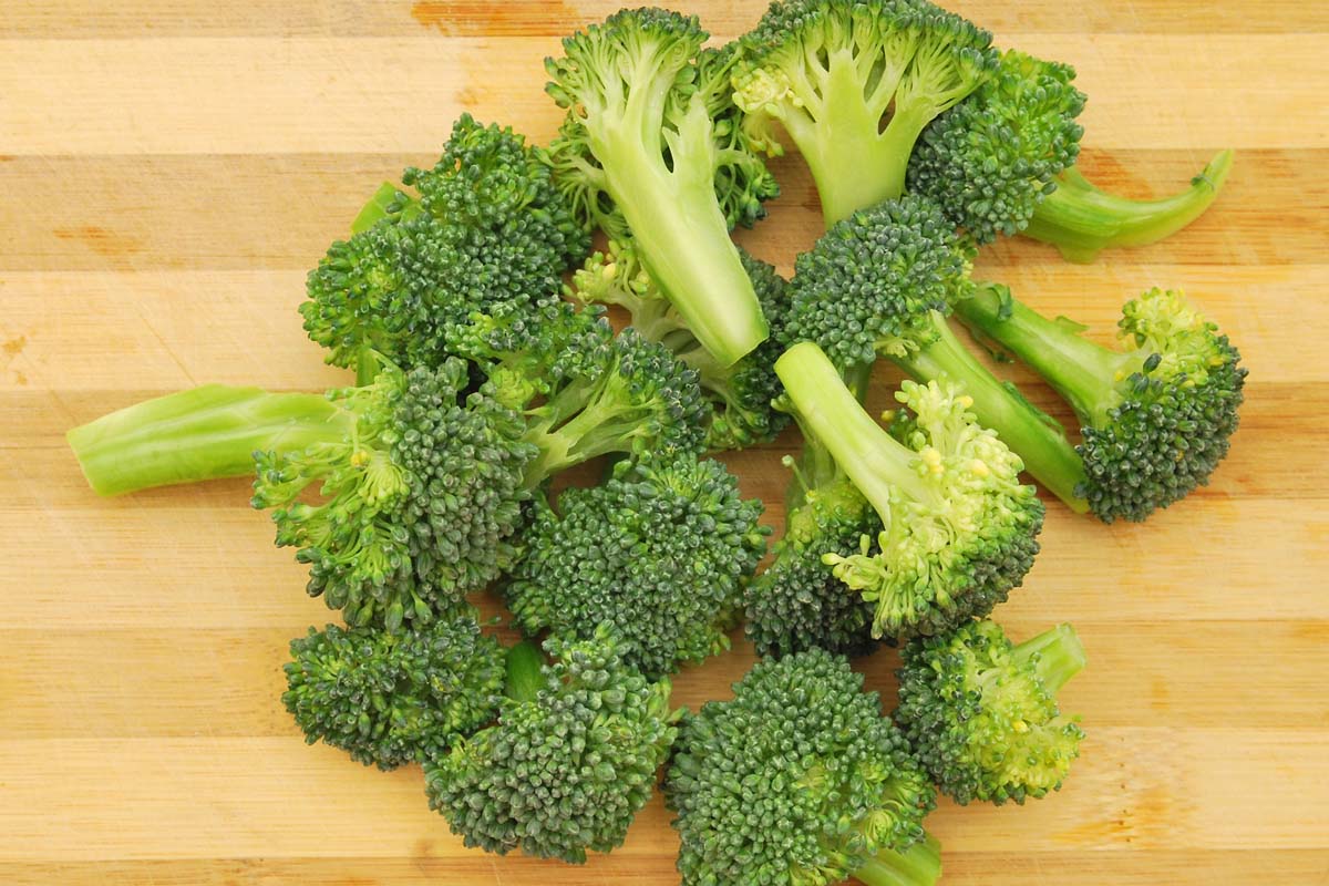 Un haut de gamme de fleurons de brocoli, coupés sur une planche à couper en bois.
