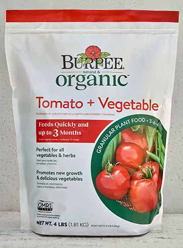 Un gros plan d'un sac d'engrais de tomates et de légumes de burpee isolé sur fond blanc.