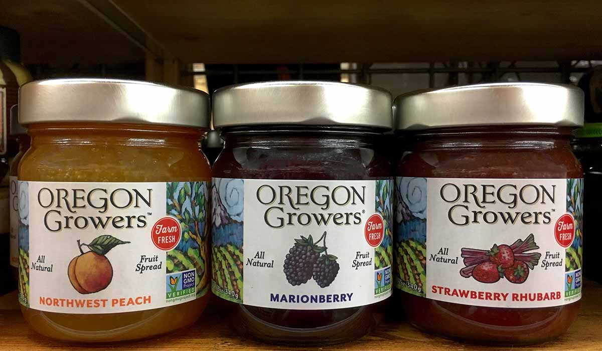 Une image horizontale en gros plan de trois pots de confiture de fruits sur une étagère d'un marché fermier.